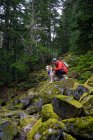 Maschio escursionista e soffice cane in piedi su rocce muschiose in montagna — Foto stock