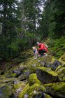 Caminhante masculino e cachorro fofo em pé sobre rochas musgosas nas montanhas — Fotografia de Stock