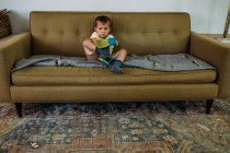 Giovane ragazzo seduto sul divano mettere su scarpe — Foto stock