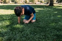 Jovem brincando na grama em um parque em um dia quente — Fotografia de Stock