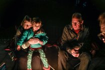 Бабуся обіймає онука, сидячи навколо вогнища надворі — стокове фото