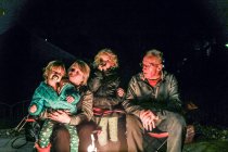 Grandparents sitting with grandchildren around firepit — Stock Photo