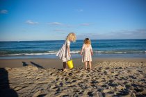 Due ragazze che giocano vicino all'oceano con il cielo blu in abiti coordinati — Foto stock