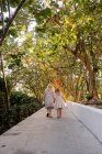Duas meninas andando no caminho de mãos dadas através de árvores — Fotografia de Stock