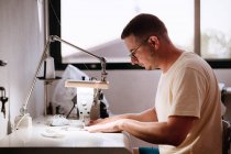 35-річний чоловік використовує швейну машинку вдома. Молодий чоловік шиє — стокове фото