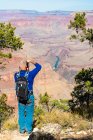 Prise de vue idyllique d'un touriste masculin prenant une photo du Grand Canyon le long d'Hermit Road, Grand Canyon National Park, Arizona, USA — Photo de stock