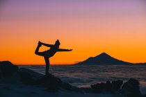 Giovane donna in posa yoga durante il tramonto con il Monte Taranaki sullo sfondo, Tongariro National Park, Nuova Zelanda — Foto stock