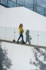Жінка з скутером, що йде на схилі — стокове фото