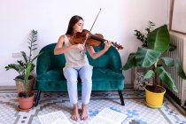 Menina sentada tocando viola, partitura em torno de seus pés descalços — Fotografia de Stock