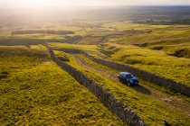Voiture conduisant sur la route de campagne anglaise avec vue sur les collines — Photo de stock