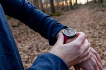 Man holding wrist watch in autumnal park — Stock Photo