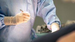 Tiro cortado de cirurgião segurando bisturi na sala de cirurgia — Fotografia de Stock
