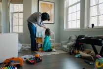 Vater und Tochter montieren Puppenhaus in chaotischem Zimmer — Stockfoto