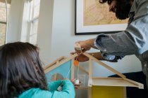Father and daughter assembling dollhouse together — Stock Photo
