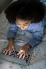 Одинадцятирічна бі-расова дівчина працює на ноутбуці на ліжку — стокове фото