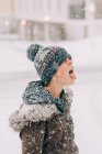 Niño con sombrero lanudo cogiendo copo de nieve en su lengua - foto de stock