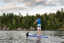 Підліток у сонячний день веслує на кораблі позашляховика на озері в Онтаріо (Канада).. — стокове фото