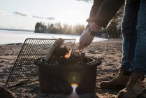Man's hands lighting a bonfire outside on a beach in Sweden — Stock Photo