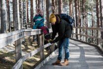 Padre aiuta la figlia a mettersi la scarpa mentre cammina nel bosco — Foto stock