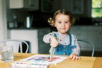 Маленькая девочка рисует акварелью за столом — стоковое фото