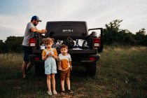 Papá y dos niños haciendo un picnic en el portón trasero del camión - foto de stock