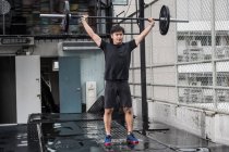 Entrenamiento de hombre en el gimnasio de la azotea en Bangkok - foto de stock