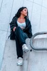 Junge schwarze Frau sitzt mit Zöpfen und blickt nach rechts — Stockfoto