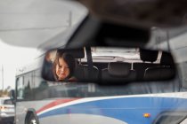 Ein süßes kleines Mädchen spiegelt sich im Rückspiegel eines Autos — Stockfoto