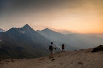 Two climbers ascend a trail at sunrise towards the Glacier Peak summit in the Glacier Peak Wilderness in Washington. — Stock Photo