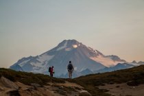 Dos escaladores ascienden a un sendero al amanecer hacia la cima del Glaciar Peak en el Glaciar Peak Wilderness en Washington. - foto de stock