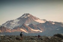 Zwei Bergsteiger steigen bei Sonnenaufgang einen Trail hinauf zum Glacier Peak Gipfel in der Glacier Peak Wilderness in Washington. (veröffentlicht: Sam Thompson und Brock Gavery) — Stockfoto