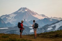 Deux alpinistes montent un sentier au lever du soleil vers le sommet du Glacier Peak dans le Glacier Peak Wilderness à Washington. — Photo de stock