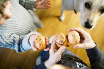 Zwei kleine Kinder halten Eier mit Zeichentrickgesichtern für Osterspaß — Stockfoto