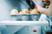 Uma caixa de ovos na geladeira com caras bobas desenhadas neles para diversão na Páscoa — Fotografia de Stock
