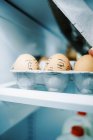 Uma caixa de ovos na geladeira com caras bobas desenhadas neles para diversão na Páscoa — Fotografia de Stock