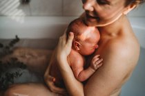 Glücklich lächelnde Mutter hält ihr Neugeborenes nach der Geburt zu Hause — Stockfoto