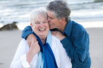 Старший чоловік цілує дружину в холодному пляжі на мисі Код. — стокове фото