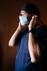 Hispânico masculino médico colocando no rosto máscara. — Fotografia de Stock