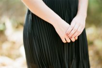 Woman holding hands in front of body in dress with simple background — Stock Photo