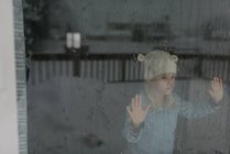 Маленькая девочка смотрит в большое окно на снег — стоковое фото