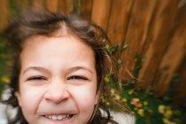 Крупним планом маленька дівчинка посміхається зовні з ефектом розмиття лінз — стокове фото