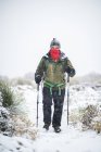 Un hombre con la cara cubierta de caminatas bajo la nieve pesada - foto de stock