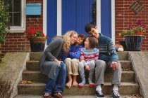 Eine liebevolle Familie kuschelt sich im Herbst vor der Haustür zusammen — Stockfoto