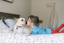 Momento doce entre cuidar menina criança doce e cão na cama — Fotografia de Stock