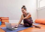 Donna che pratica yoga con computer portatile a casa sua — Foto stock