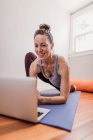 Frau praktiziert Yoga mit Laptop zu Hause — Stockfoto