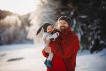 Padre e bambino sorridenti nel paese delle meraviglie invernale pieno di neve nel bosco — Foto stock