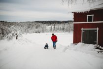 Père tirant son fils en traîneau dans la campagne norvégienne en hiver froid — Photo de stock
