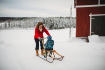 Grandma on old antique sleigh with grandchild in farm in Norway — Stock Photo