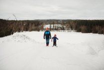 Father and son walking up a slope with skis in snowy winter day Norway — Stock Photo